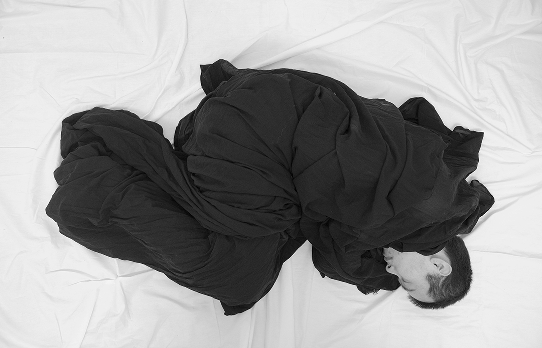 Performance textile, figure enveloppée de tissu noir